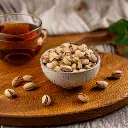 Firefly A small, handcrafted ceramic bowl filled with unsalted pistachios, placed on a wooden tray a (2).webp